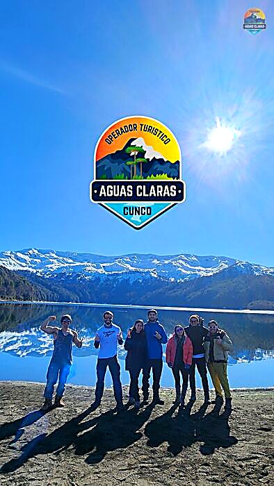 Pasajeros de Turismo Aguas Claras en el tour a Conguillío, con lago y montañas nevadas de fondo