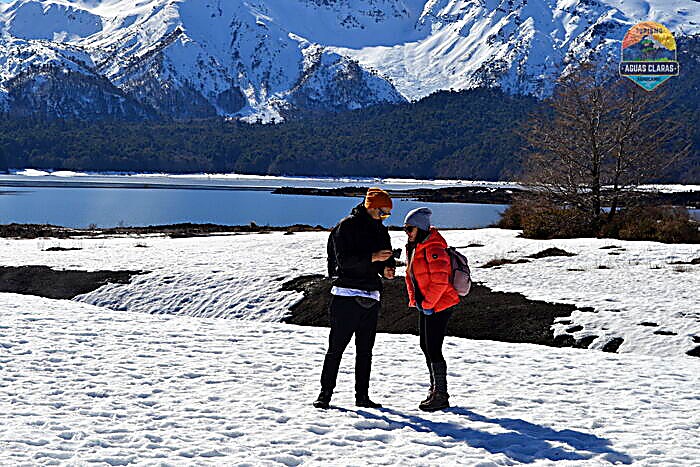 Visitantes conversando junto al lago Conguillío nevado